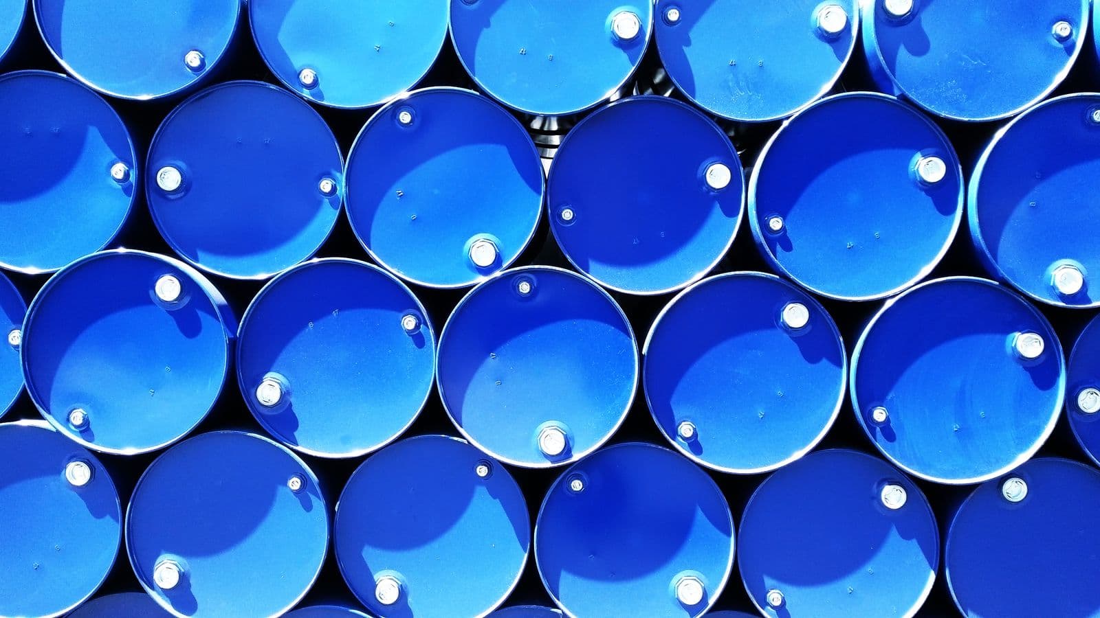 Rows of stacked blue industrial chemical drums viewed from above at a storage facility.