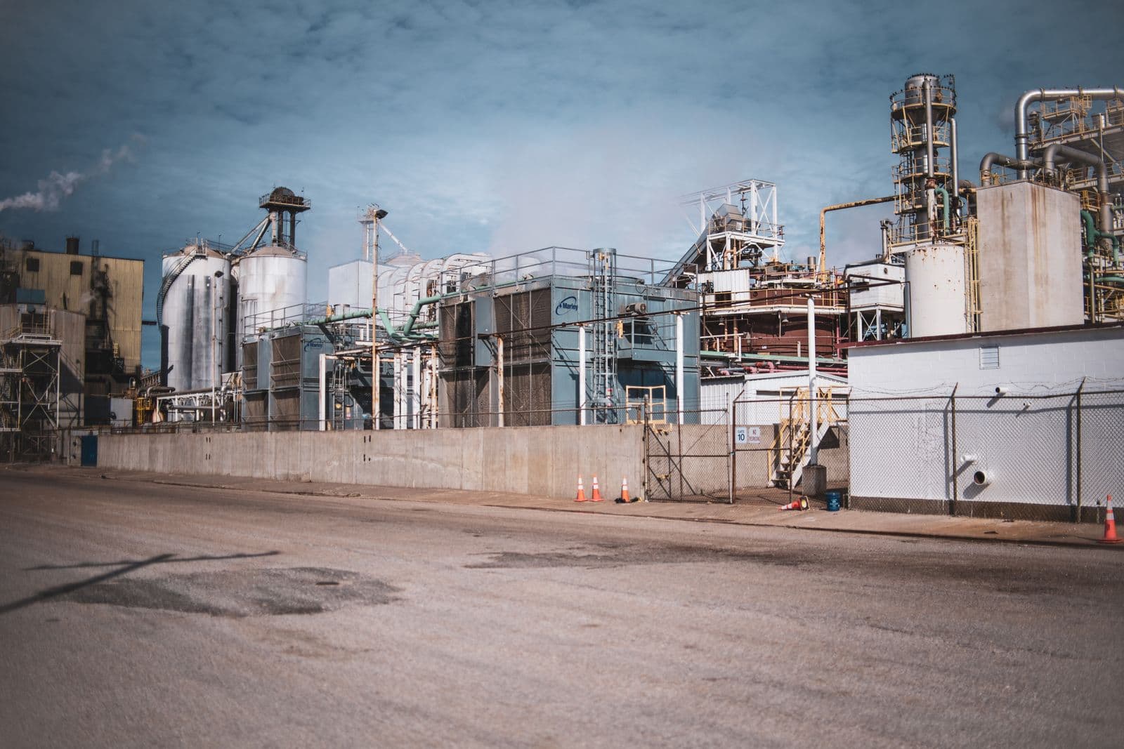 An industrial plant with aboveground steel tanks and process structures under an open sky.